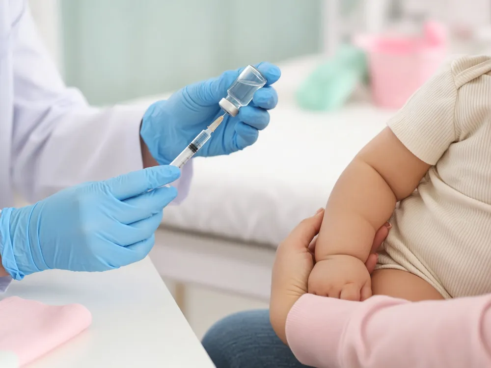 Arts maakt een vaccinatie klaar voor een baby op schoot bij een ouder