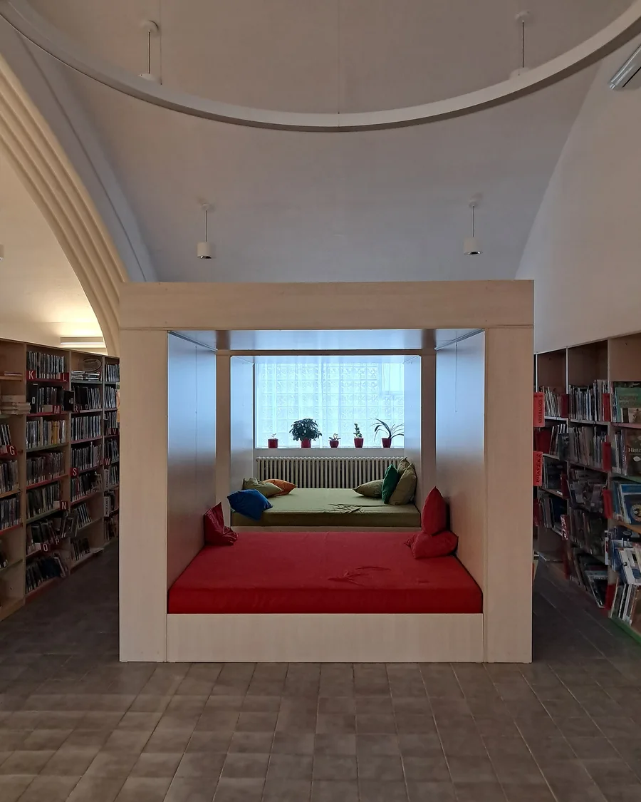 Een gezellige leeshoek met rode kussens in een kinderbibliotheek