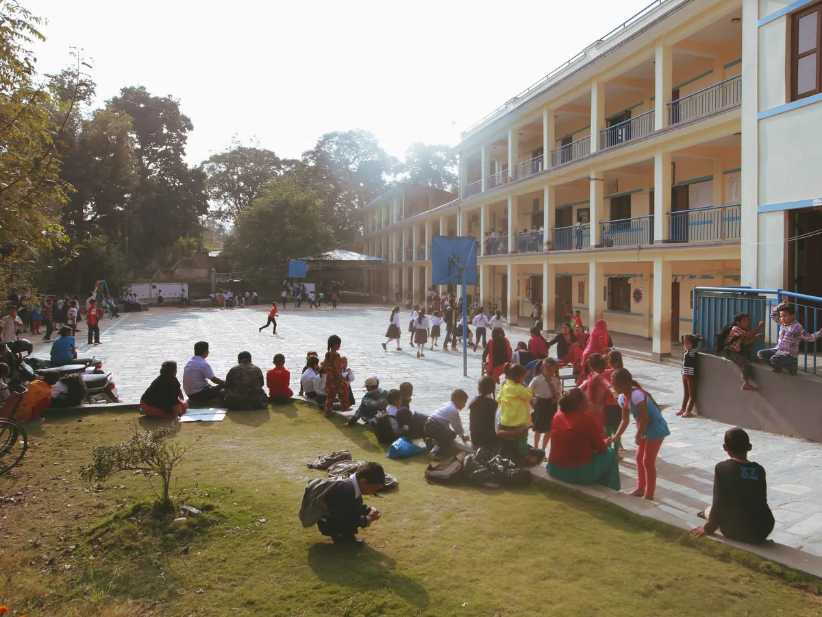 Kinderen spelen en zitten in groepjes op een zonnig schoolplein tijdens de pauze