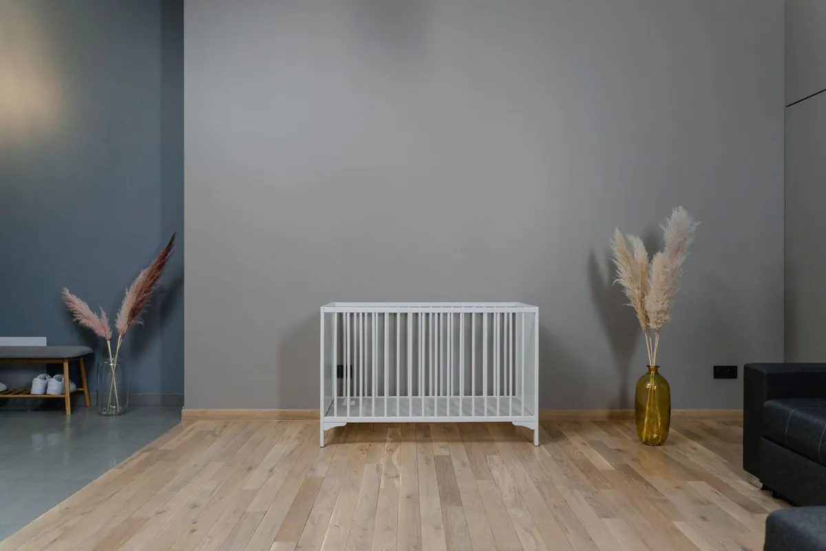 Leeg wit babybedje op een houten vloer in een lichte, sobere kamer