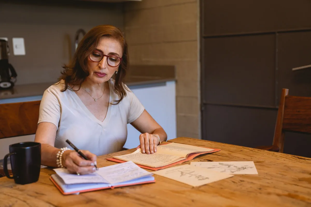 Moeder zit aan de keukentafel en maakt aantekeningen in een werkboek